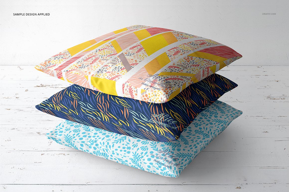 PSD mockup set displaying three decorative pillows with unique designs, arranged in a neat pile against a light background.