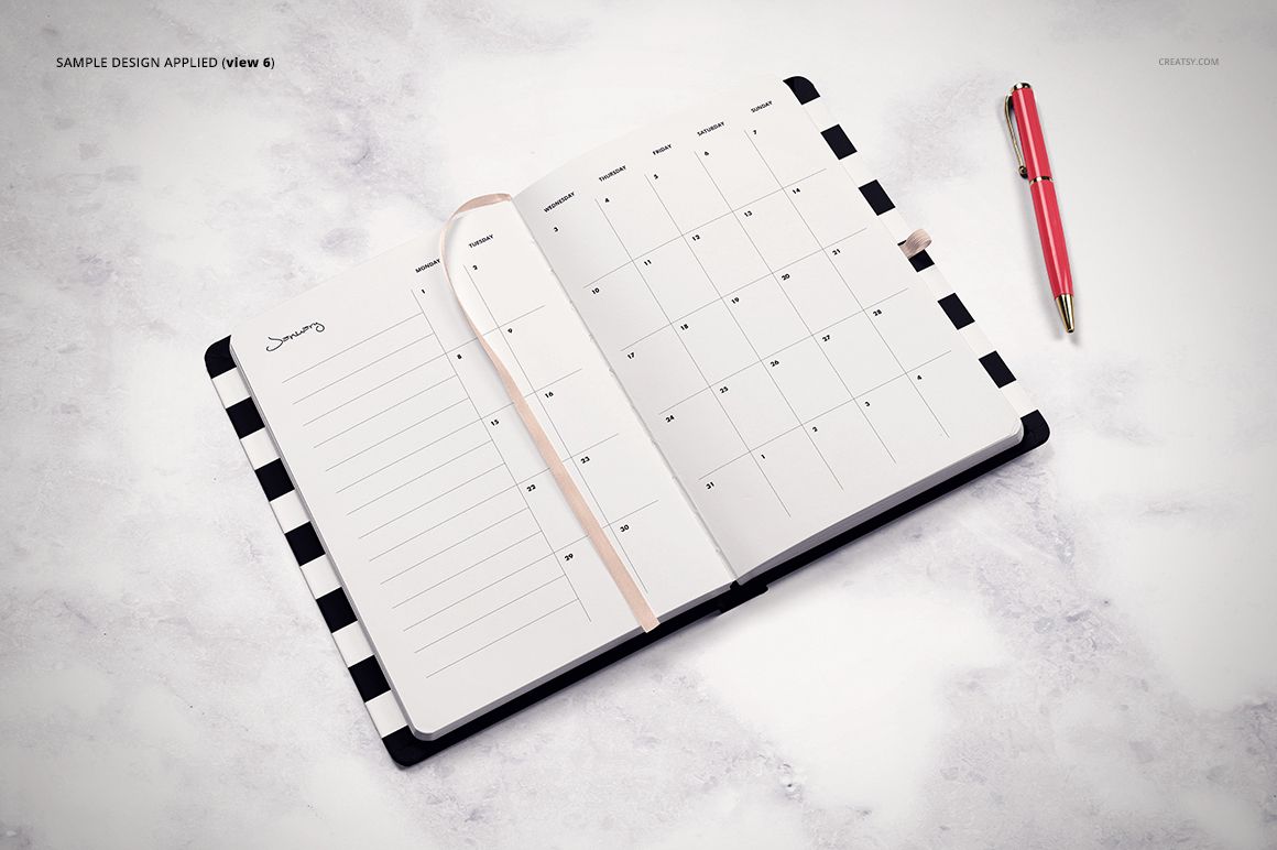 Top view of an open planner mockup with a striped edge, blank calendar pages, and a pink pen beside it.