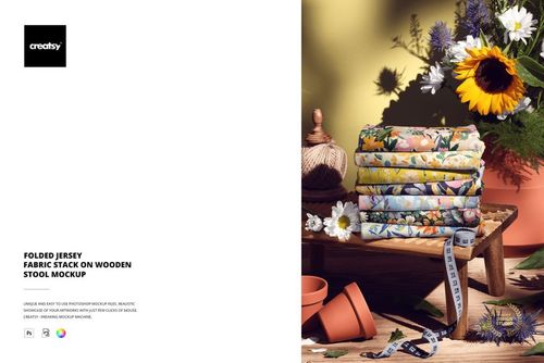 PSD mockup showing a pile of patterned jersey fabrics on a rustic stool, with sunflowers, daisies, and measuring tape nearby.