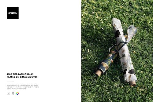 Two fabric rolls with different patterns tied with string, lying on green grass in a top view mockup scene.