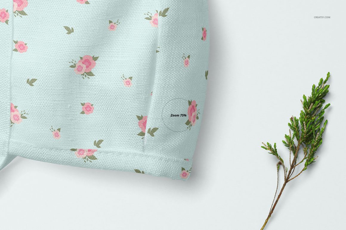 Baby bonnet mockup showing textured light blue material with scattered pink flowers, displayed beside a green plant.