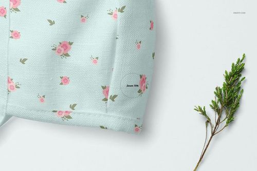 Baby bonnet mockup showing textured light blue material with scattered pink flowers, displayed beside a green plant.