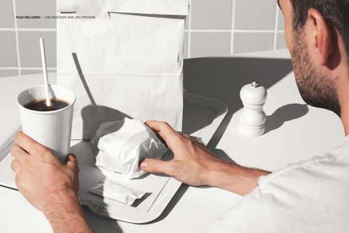 Fast food restaurant scene showing white packaging mockup, tray with burger, drink, and salt shaker on a tiled background.