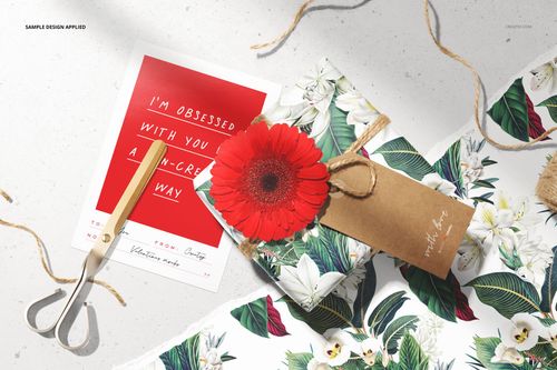Top view of a Valentine's stationery mockup set with floral wrapping paper, scissors, red card, and a gift tag.