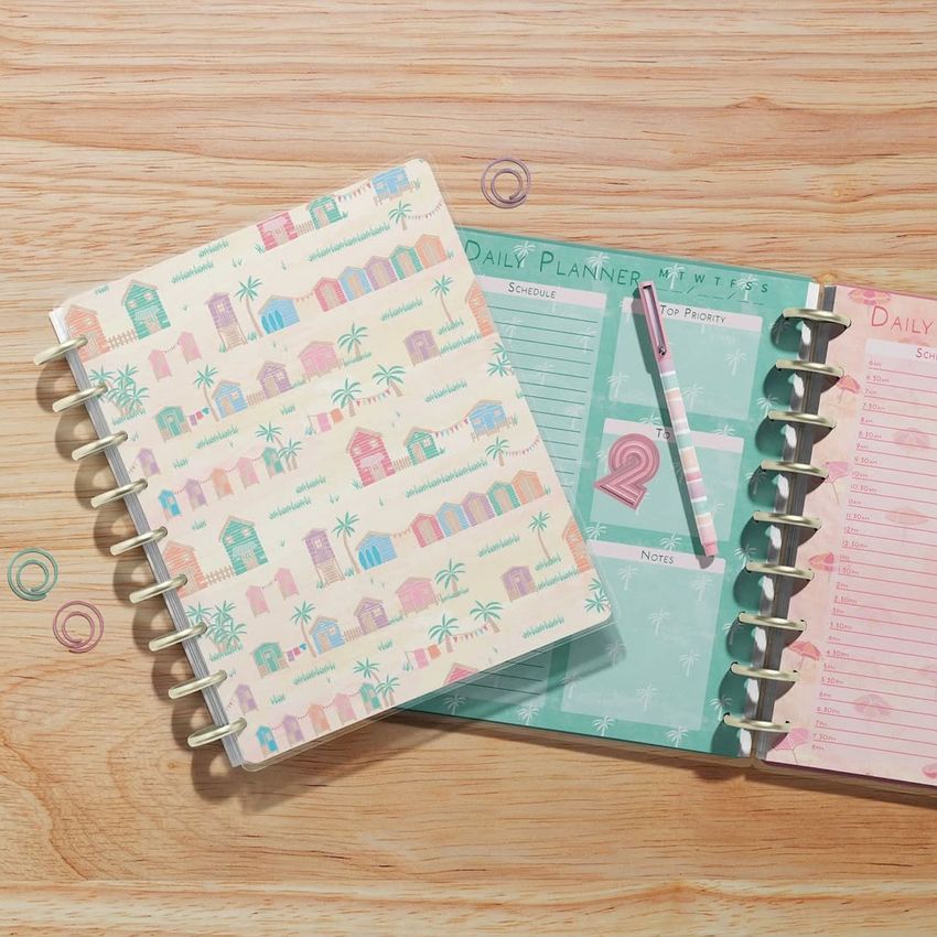 Two spiral-bound planner mockups seen from above, featuring pastel covers and open pages with lined sections and text.