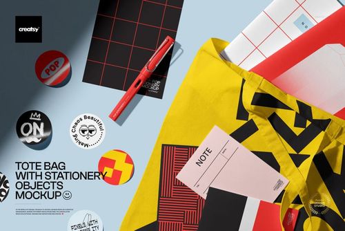 PSD mockup featuring a tote bag with geometric design, placed among pens, note cards, and graphic stickers.