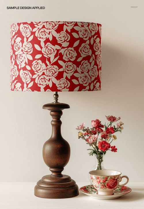 PSD mockup of a wooden table lamp with a patterned drum shade, styled with a teacup and red flowers on a neutral background.