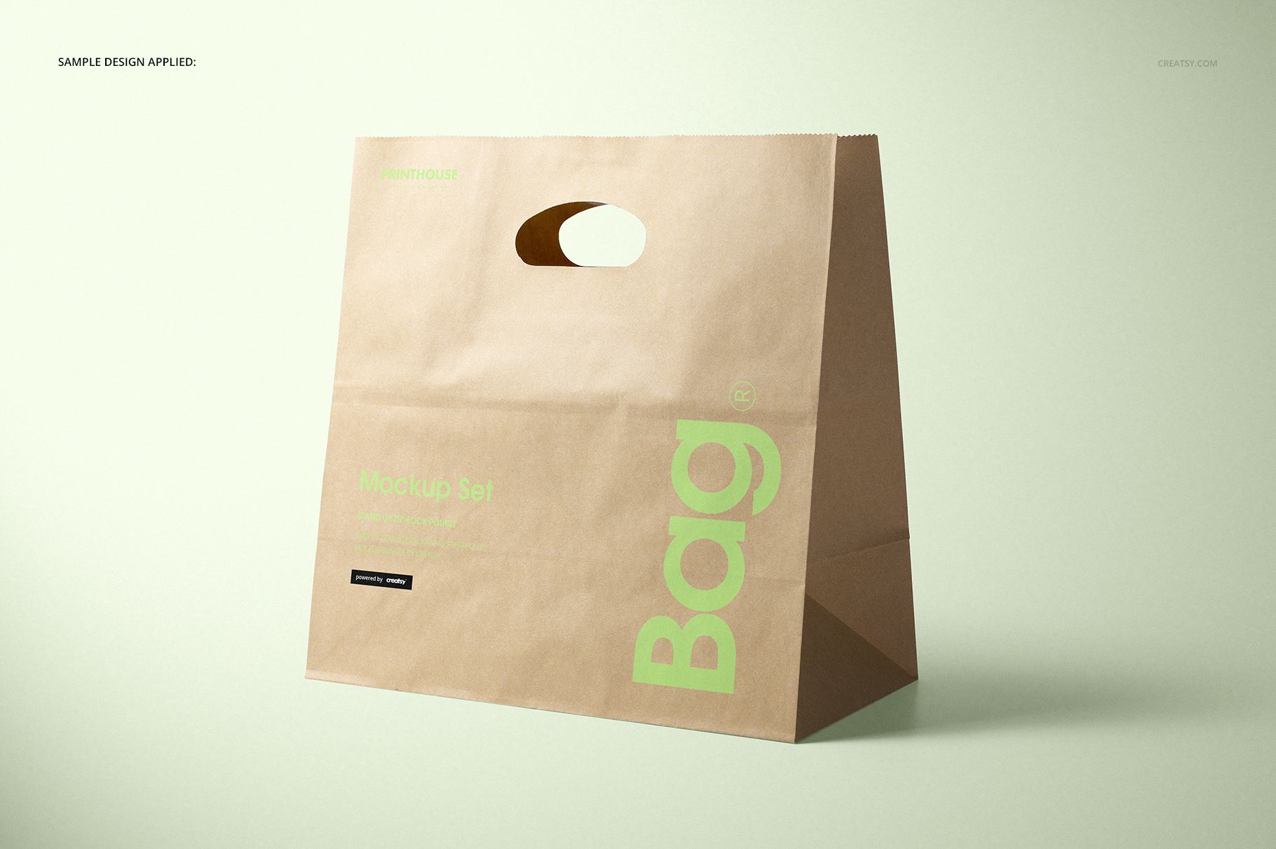 Die cut kraft paper bag mockup shown in three-quarter view, natural brown color with green print and oval handle opening.