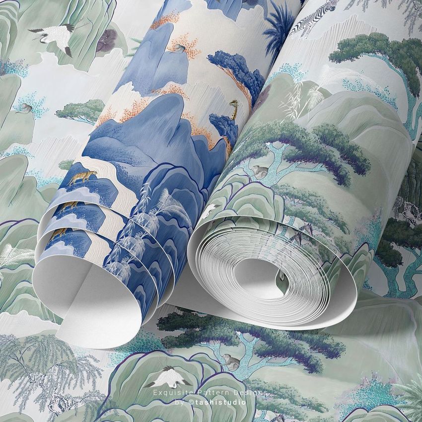 Paper wallpaper mockup showing two rolled sheets with artistic landscape patterns in blue, green, and beige tones on a flat surface.