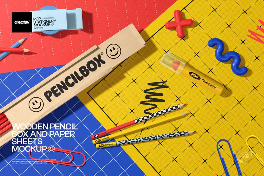 Stationery mockup featuring a wooden pencil box, vibrant pencils, and grid paper sheets arranged on a desk.