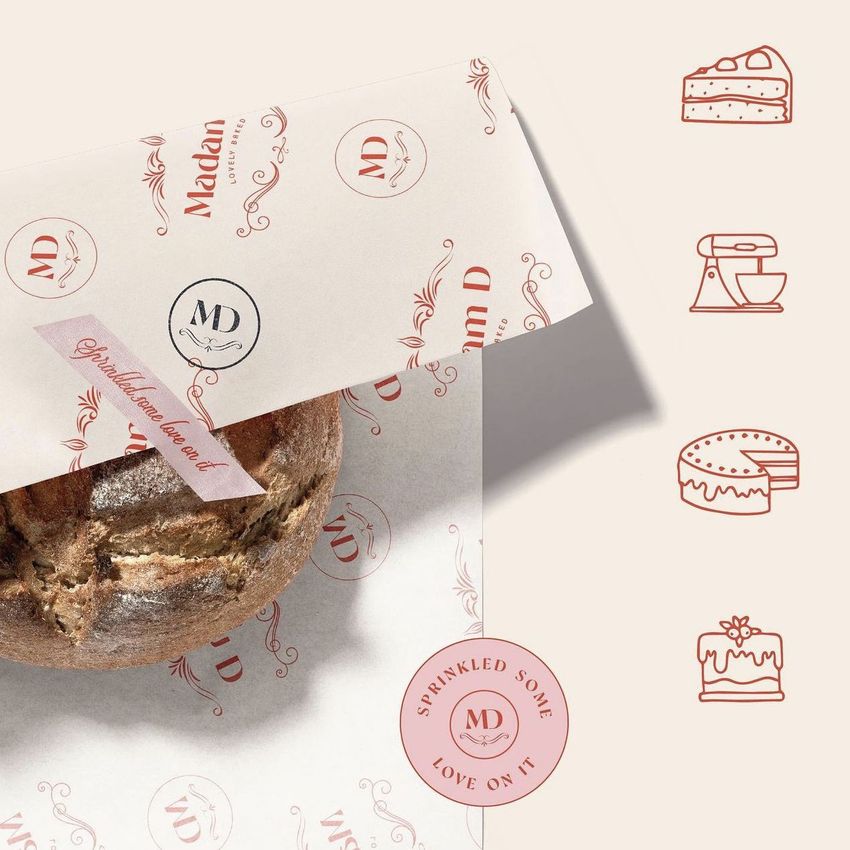 Bakery packaging mockup featuring a round loaf of bread partially wrapped in patterned food safe paper with pink accents and visible text.