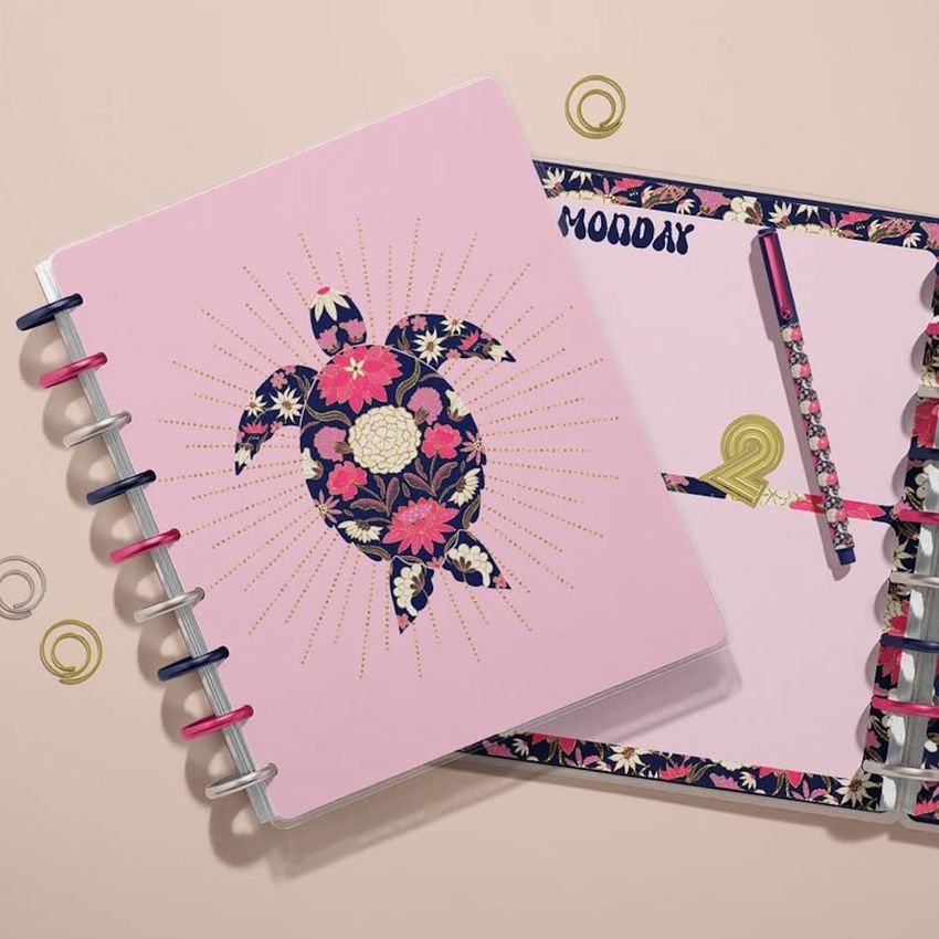 Two spiral-bound planner mockups with floral sea turtle artwork and decorative patterns, shown from above on a neutral background.