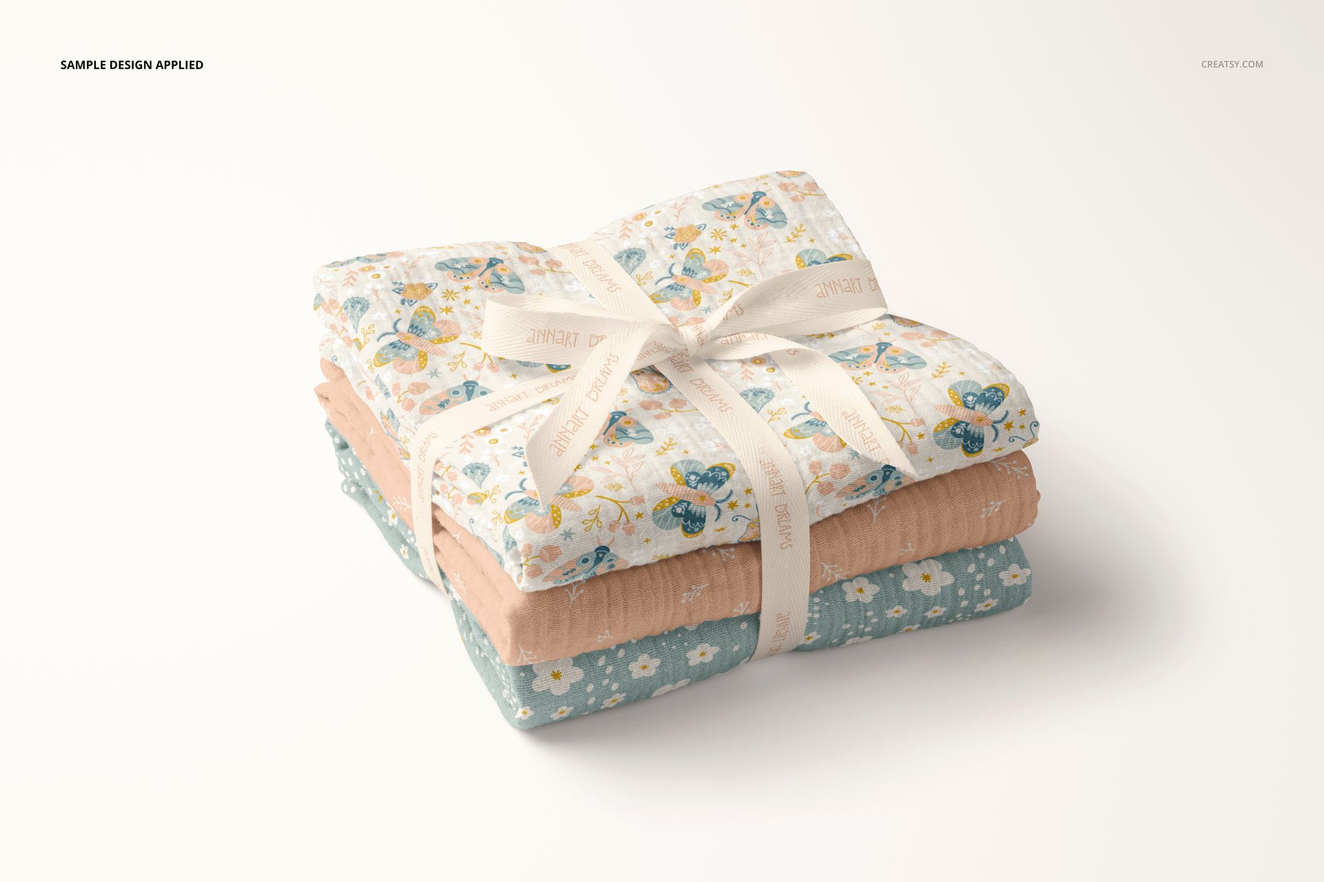 PSD mockup showing a trio of crinkle muslin swaddle blankets featuring soft colors and delicate prints, tied together neatly.