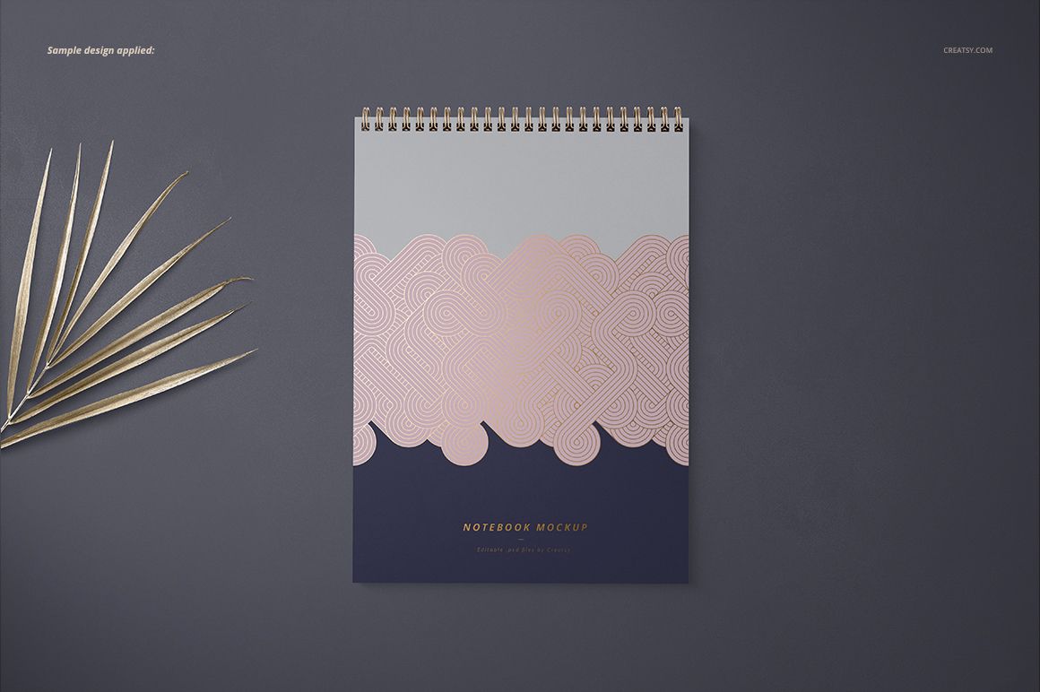 Front view of an A4 spiral notebook mockup with a geometric pink and gray design, placed on a dark surface.