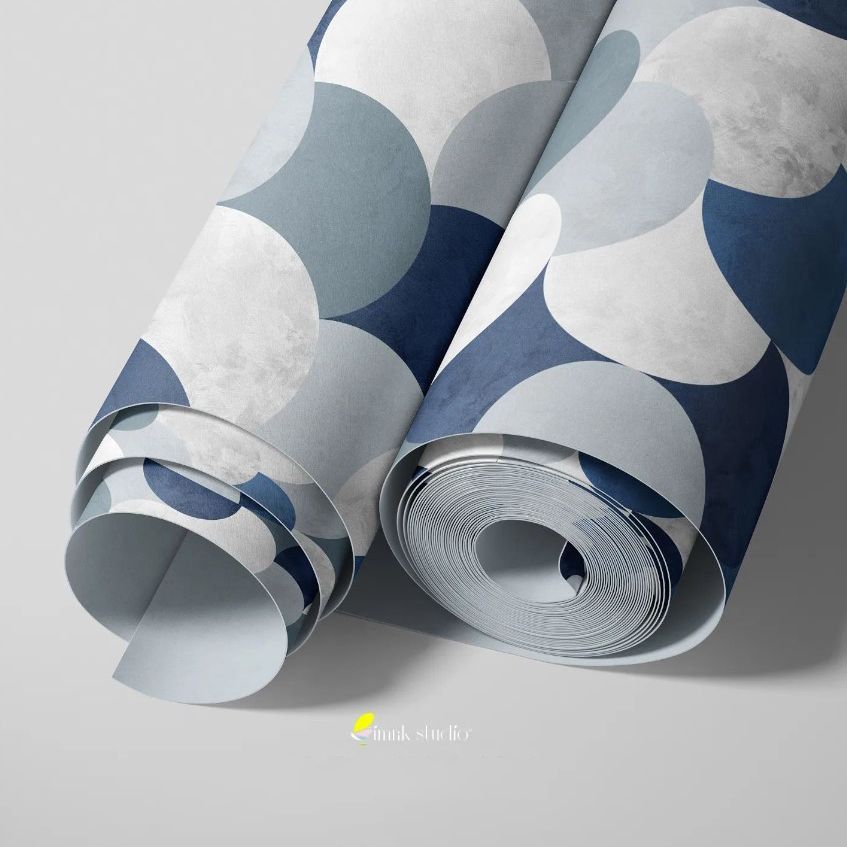 Paper wallpaper mockup showing two rolled sheets with a geometric circle pattern in shades of blue and gray on a light surface.