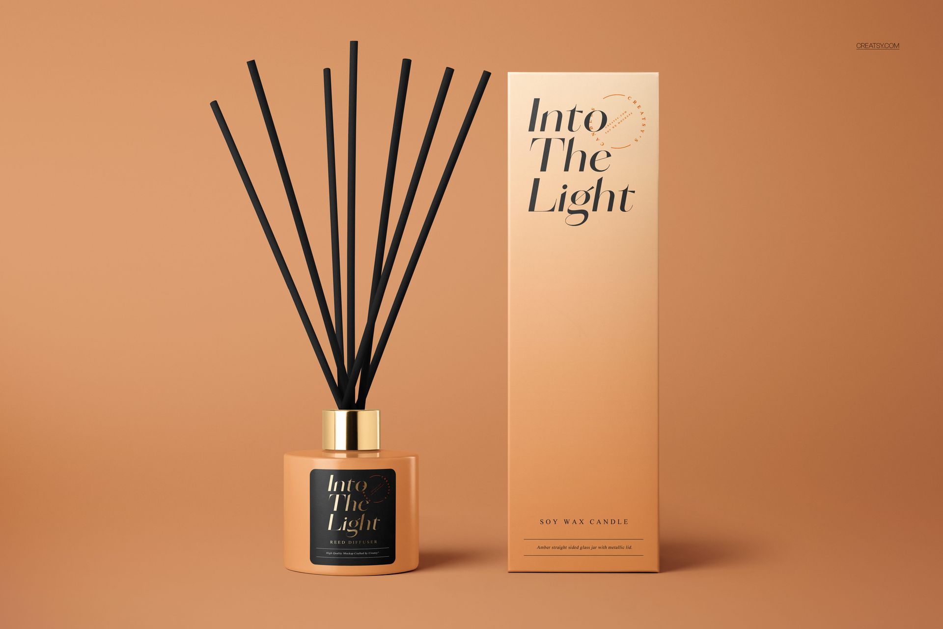 Painted glass reed diffuser mockup with gold cap and black label beside a rectangular box, both on a tan surface.