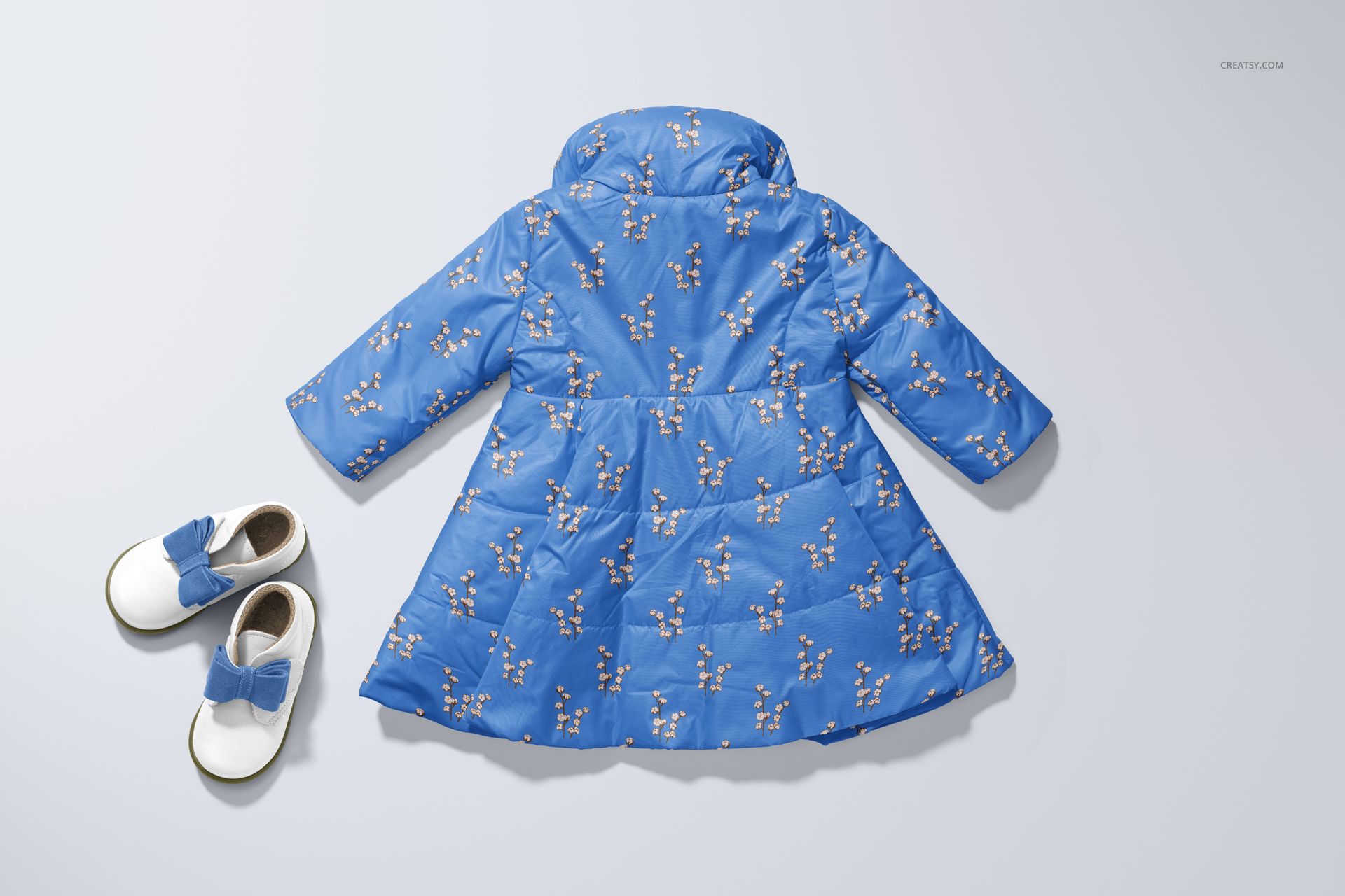 PSD mockup of a blue baby coat with a floral print, shown from the back next to white shoes with blue bows.