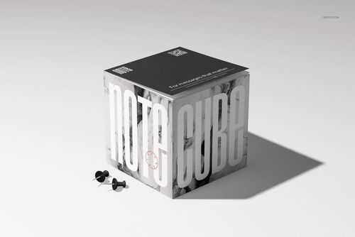 Stationery note cube mockup featuring large vertical lettering, a dark lid, and push pins beside the cube.