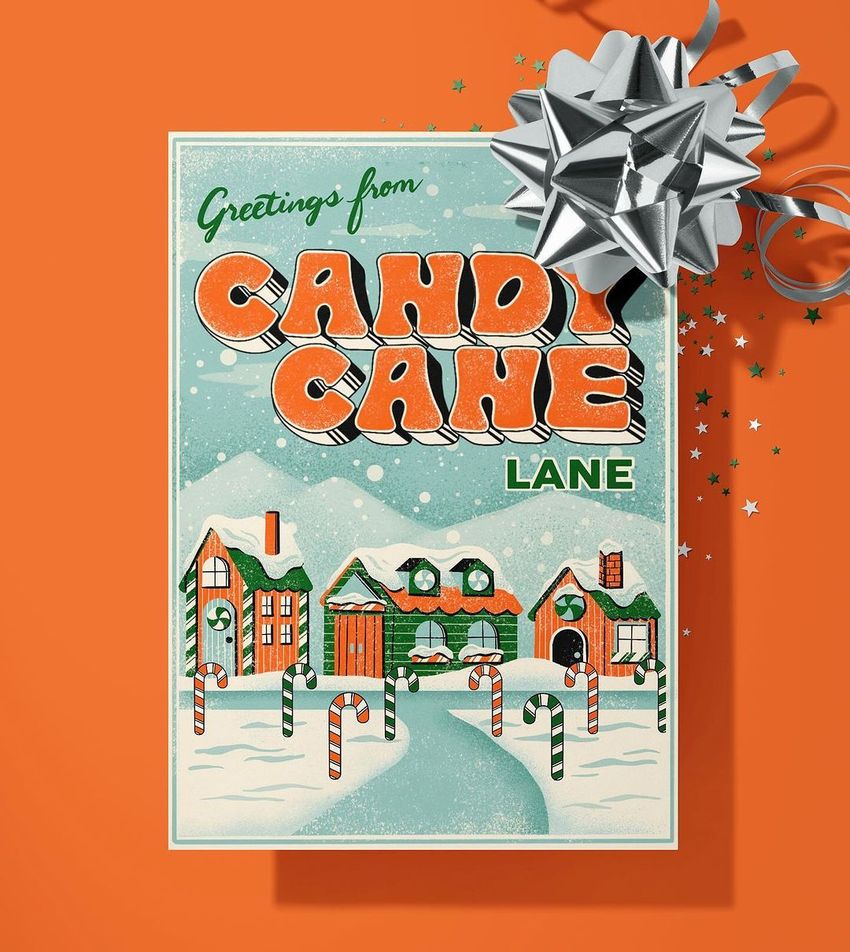 Greeting card mockup with a festive winter village scene, candy canes, and a silver ribbon bow on an orange background.