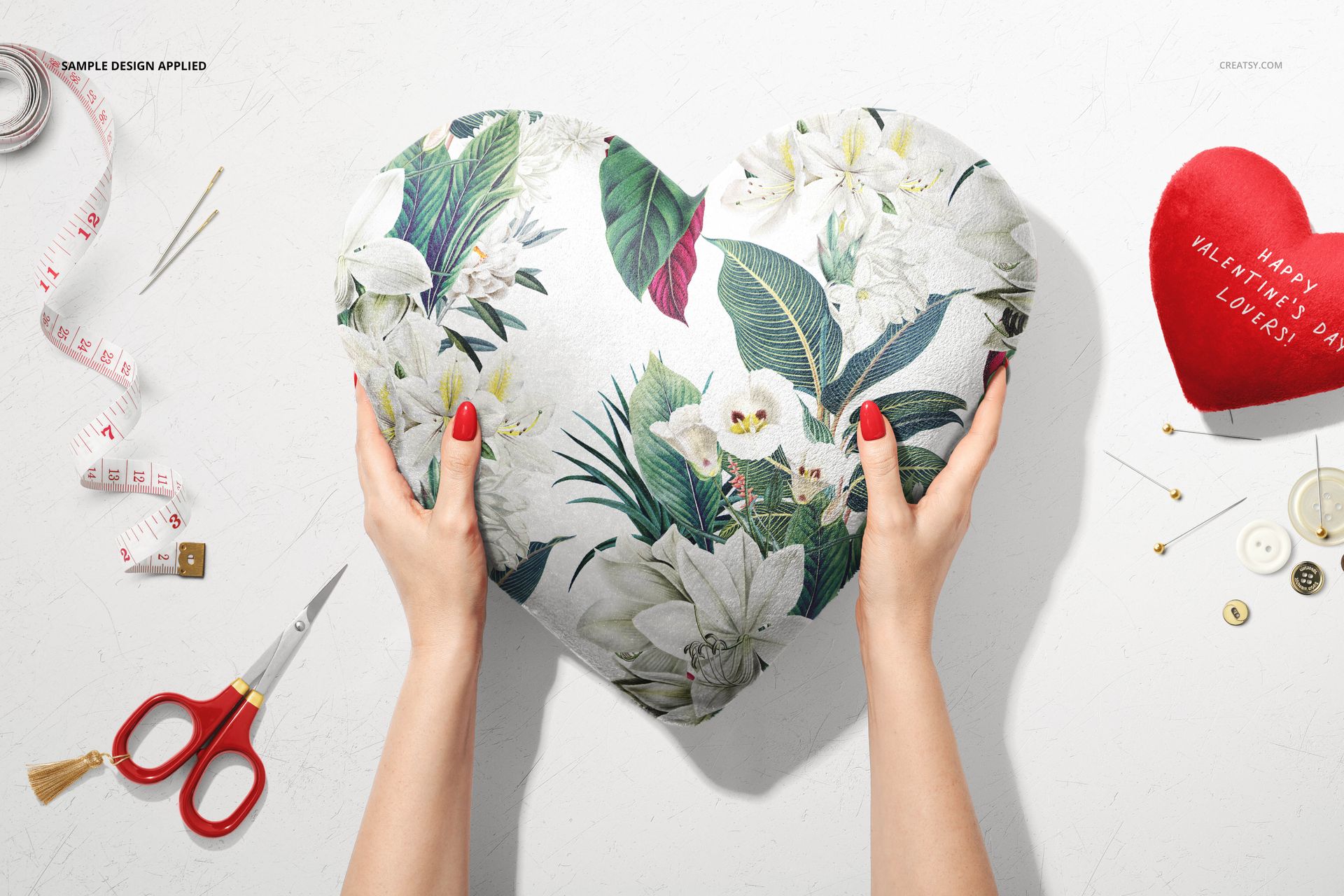 Valentine’s mockup scene with a floral heart pillow, red scissors, tape measure, buttons, and a red heart-shaped item.