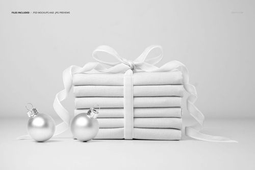 Stacked fabric mockup arranged as a gift, with a velvet ribbon and two metallic baubles on a plain background.