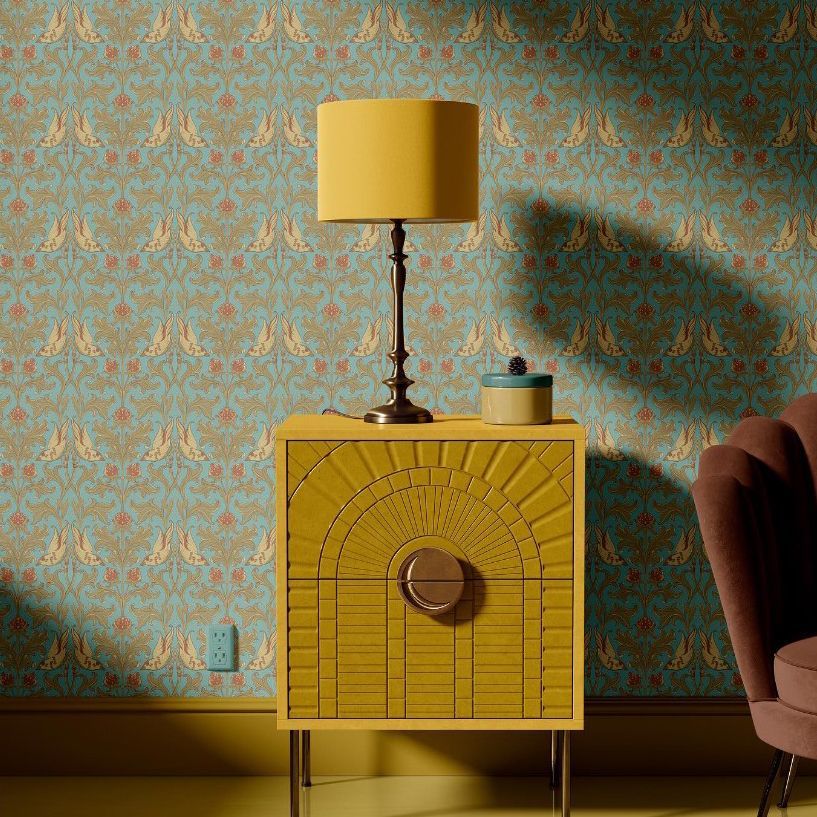 Drum lamp shade mockup on a brass lamp sits atop a yellow cabinet, with patterned wallpaper and a small plant nearby.