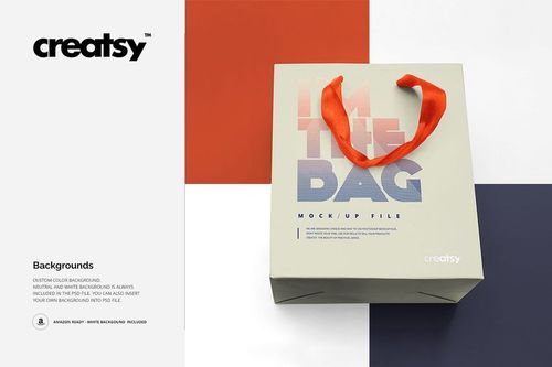 Square gift bag mockup with bold orange ribbon handles, shown from above on a multicolored geometric background.