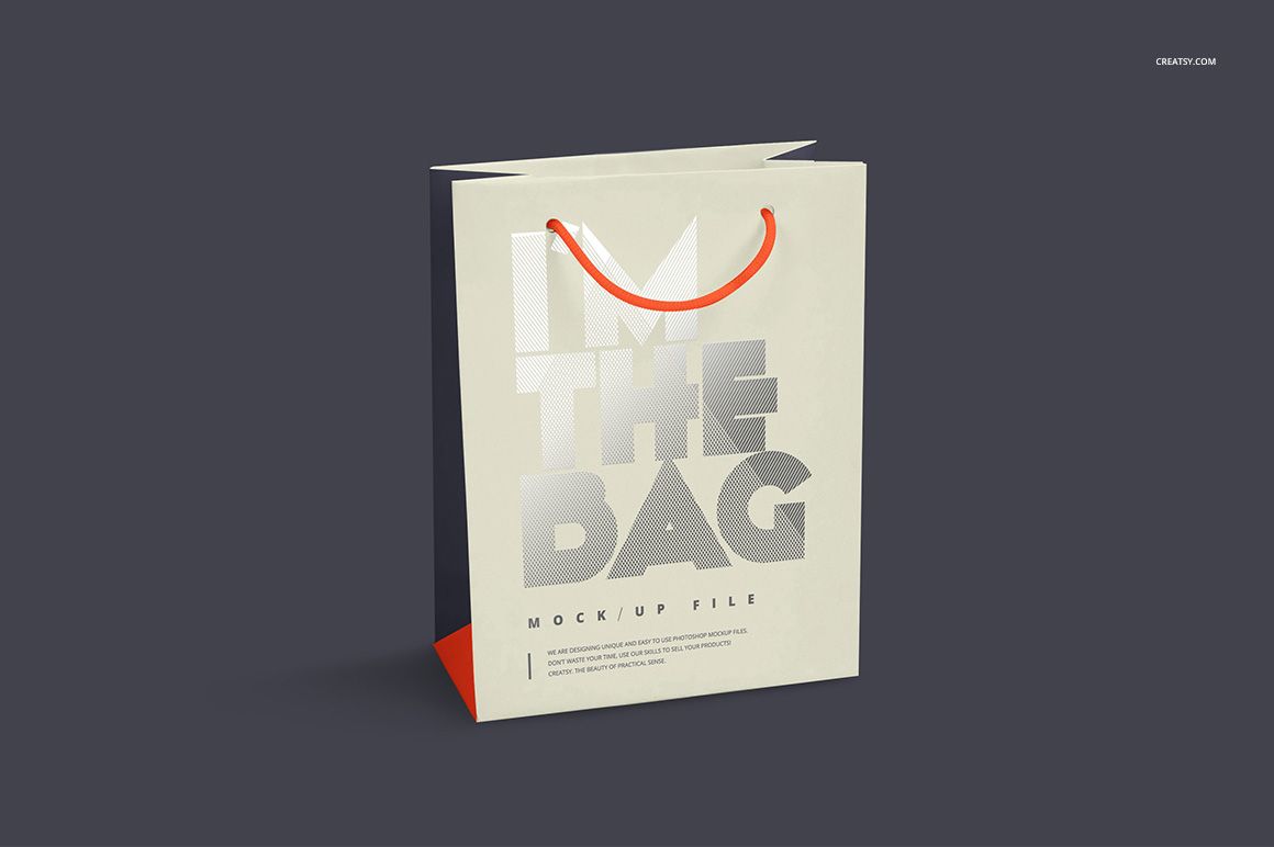 Front view of a paper bag mockup with silver foil text, orange handles, and a dark neutral background.