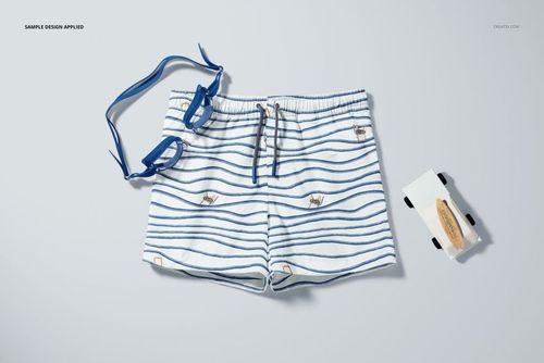 Top view of kids swim shorts mockup featuring blue stripes and playful crab patterns, shown with matching goggles.