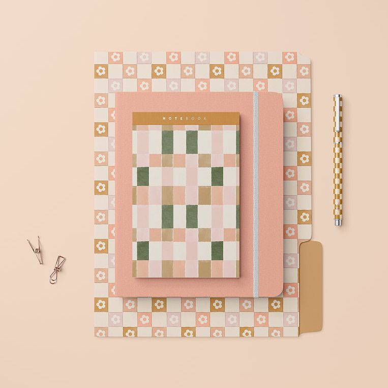 Stationery set mockup featuring a checkered notebook, floral folder, and matching pen on a beige background.