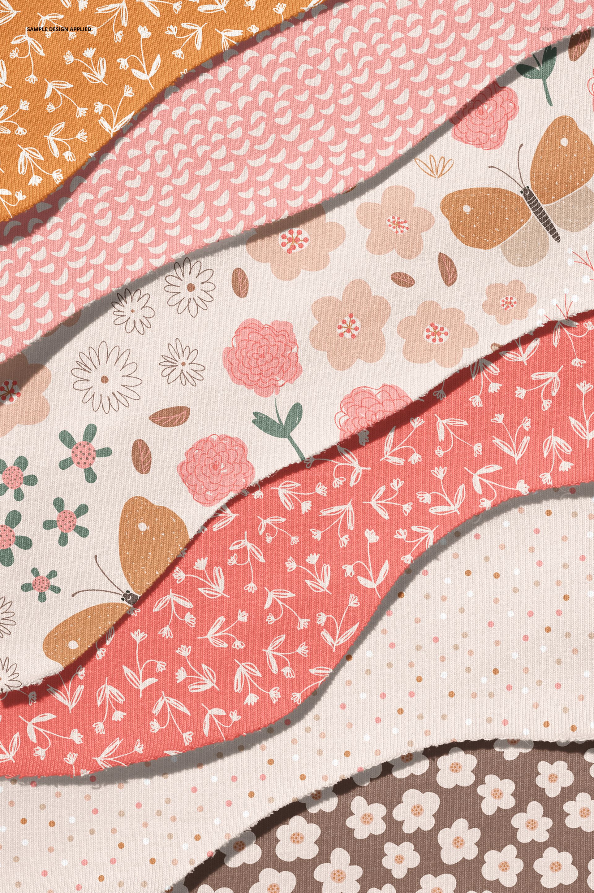 PSD mockup of multiple jersey fabric strips with torn edges, each decorated with different pastel floral and butterfly motifs.