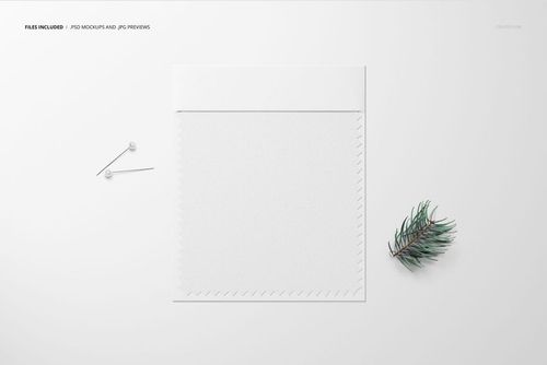 Fabric swatch mockup displayed on a white surface with two pins and a small pine branch beside it, top view.