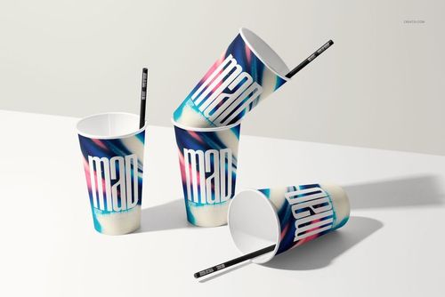 PSD mockup of paper cups with graphic prints and black straws, displayed on a clean white tabletop in bright lighting.
