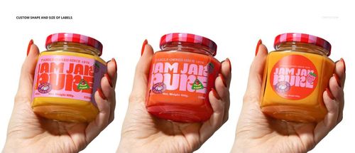Close-up of a human hand with orange nails holding a jam jar mockup, featuring a bright label and patterned lid.
