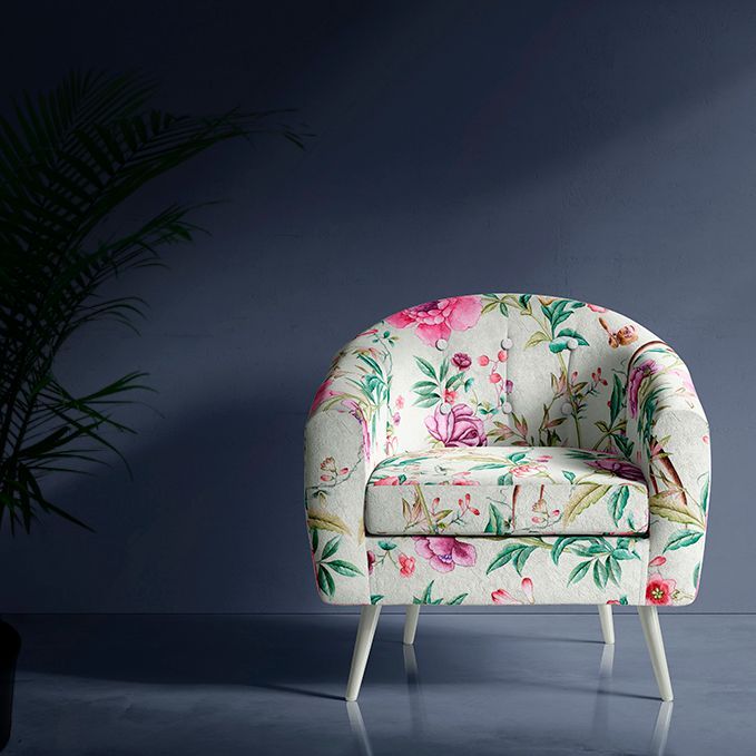Floral armchair mockup in a modern interior scene with a dark blue wall, glossy floor, and a leafy plant shadow on the left.