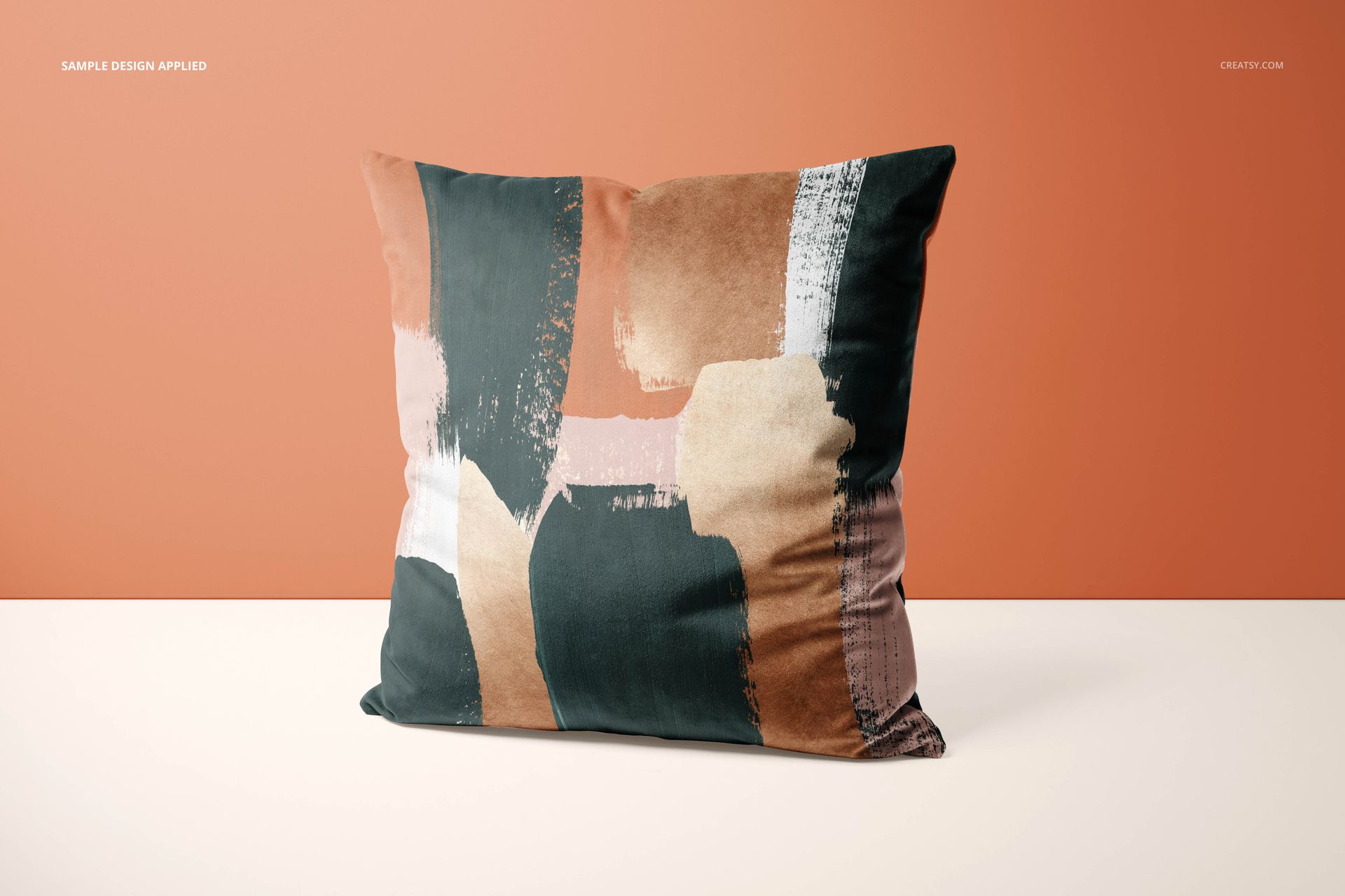 Front-facing cushion mockup with painted pattern in green, tan, and white, set on a minimalist two-color surface.