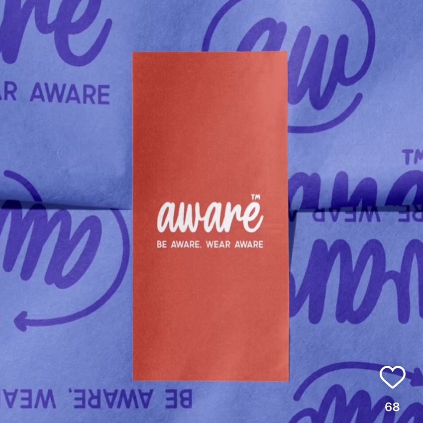 Sticker mockup featuring a red rectangular sticker with white text placed on blue wrapping paper with repeating purple graphics.