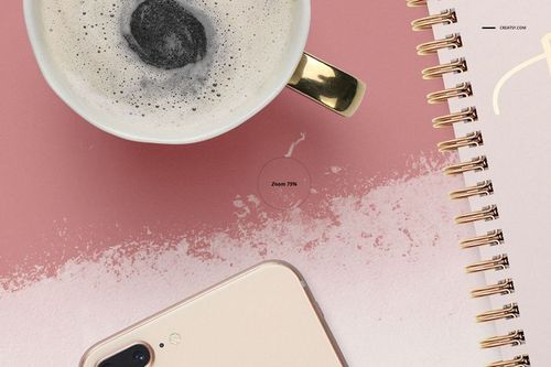 PSD mockup featuring an A4 notebook with gold spiral binding, pink surface, coffee cup, and smartphone in the scene.