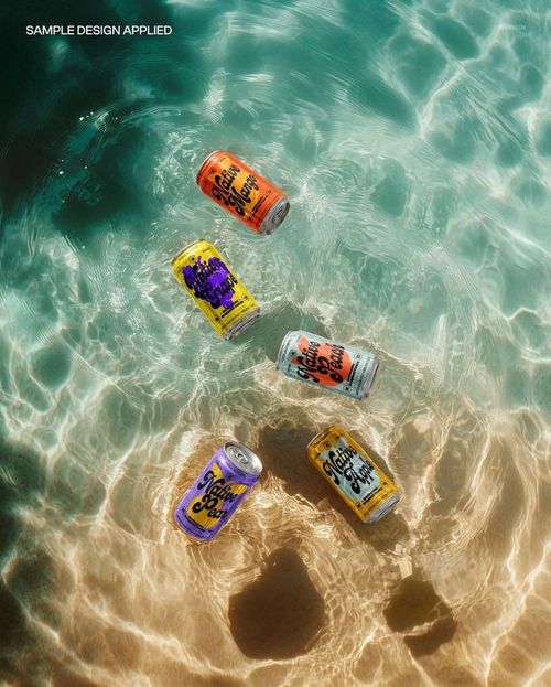 Top view of five drink cans in vibrant orange, yellow, and purple designs submerged in transparent water mockup.