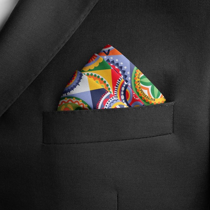 Pocket square mockup featuring a colorful patterned handkerchief in the breast pocket of a black suit jacket, seen close up.