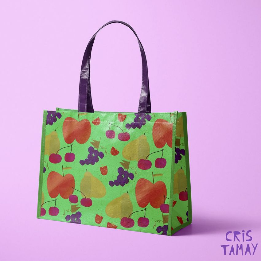 Laminated non-woven tote bag mockup with a colorful fruit pattern featuring apples, cherries, and grapes on a light purple background.