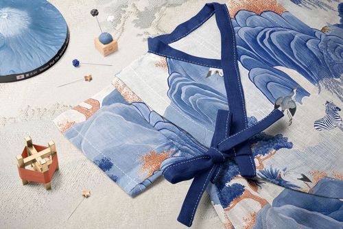 Baby romper mockup with traditional Japanese landscape print, styled with a temari ball, needle pad, and wooden blocks.