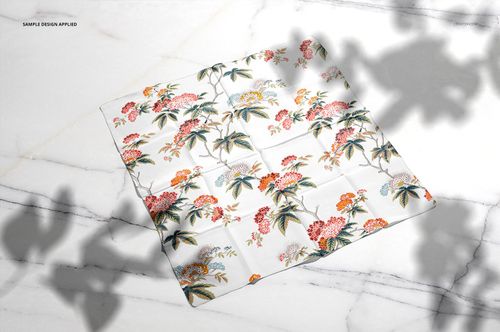 Square silk scarf mockup featuring a botanical design, shown from above on a white marble background with shadows.