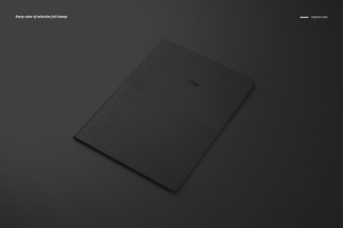 Angled top view of a classic A5 notebook mockup with a black cover and subtle dotted pattern on a dark background.