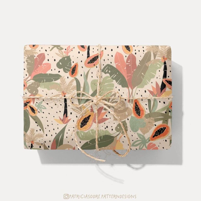 Gift wrapping paper mockup featuring a rectangular box wrapped in jungle-themed paper with papaya and leaf illustrations, tied with twine.