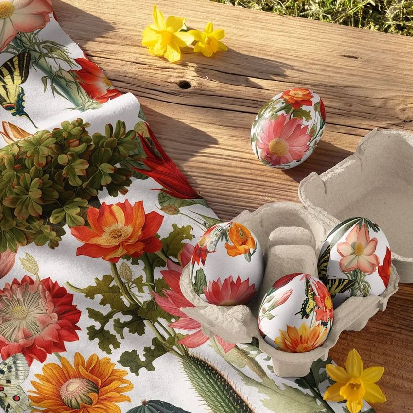 Cotton fabric mockup with a floral pattern displayed beside decorated Easter eggs in a carton on a wooden surface.