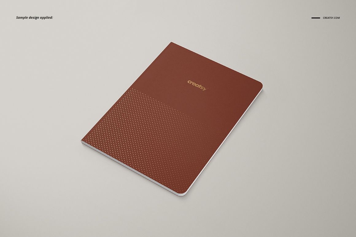 Angled top view of an A5 notebook mockup with a brown cover, gold text, and geometric dotted pattern detail.