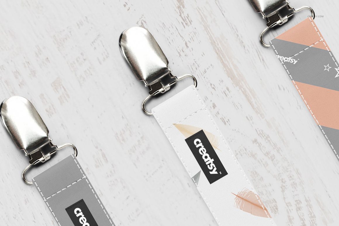Close-up of pacifier clip mockup set showing three fabric straps with editable labels and soft color designs.