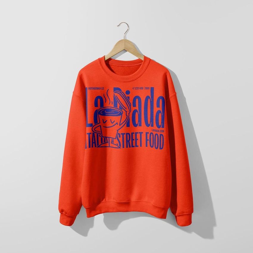 Sweatshirt mockup featuring a bright orange crewneck on a wooden hanger, with bold blue graphic and text on the front.