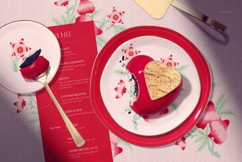 Top view of a PSD mockup featuring a round cake plate and dessert plate with red borders, floral motifs, and a heart-shaped cake.